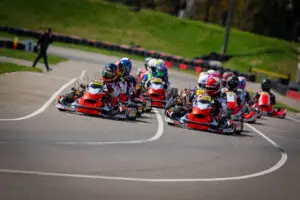 26HRKCR2CKN3435 Hamilton Karting Complex Hamilton Karting Complex Group of go-karts with drivers leaning into a sharp turn on a race track; colorful helmets and suits visible under bright daylight.